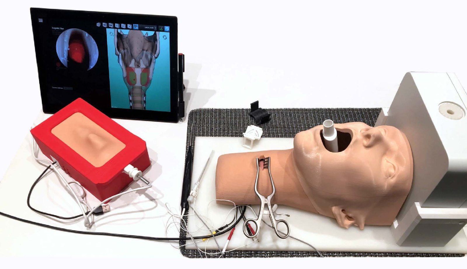 Complete simulator setup with box simulator, head and neck replica with surgical instruments, tracking field generator and tablet computer